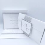 Προσκλητήρια γάμου πολυτελείας U025 glitter silver λευκό με γκλίτερ, ασημί λεπτομέρειες και μονογράμματα, της εταιρίας NewAge invitations